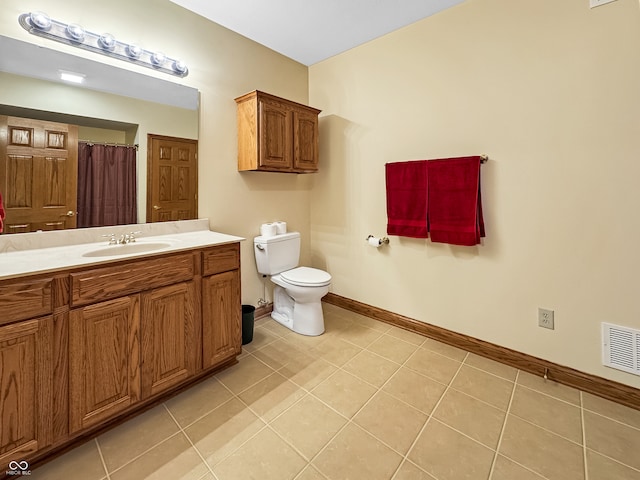 bathroom with toilet, vanity, and tile patterned flooring