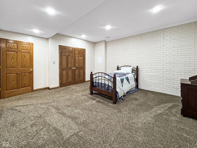 carpeted bedroom featuring a closet and brick wall