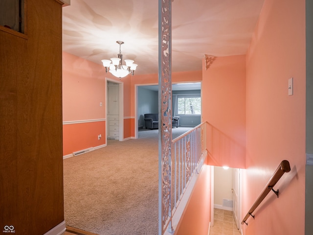 hall featuring light carpet and a notable chandelier