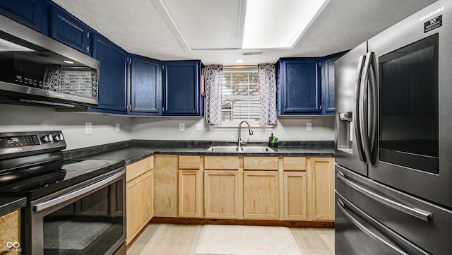 kitchen featuring appliances with stainless steel finishes, light hardwood / wood-style flooring, blue cabinets, and sink