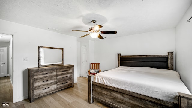 bedroom with a textured ceiling, light wood-type flooring, and ceiling fan