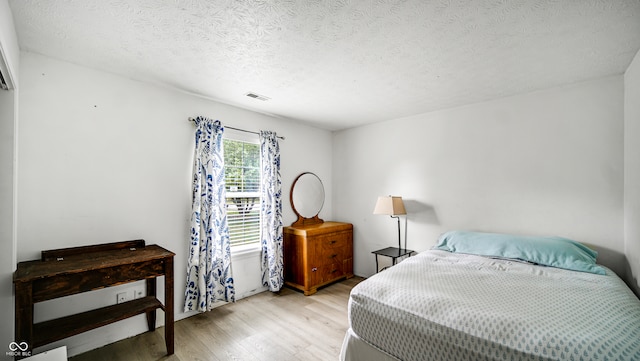 bedroom featuring light hardwood / wood-style flooring and a textured ceiling