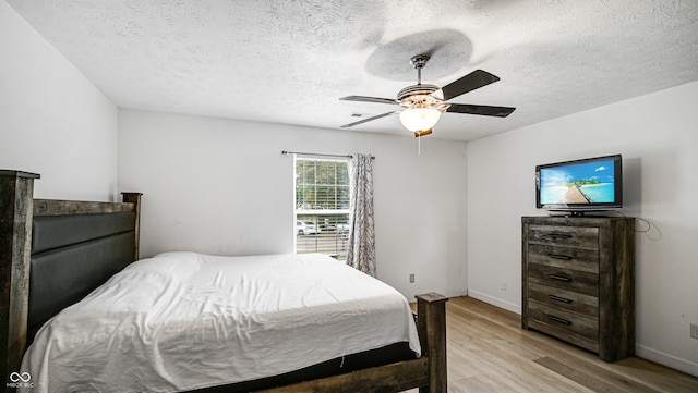 bedroom featuring light hardwood / wood-style floors, a textured ceiling, and ceiling fan