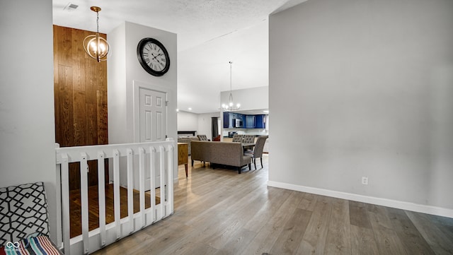 hallway with a high ceiling, a textured ceiling, and light wood-type flooring