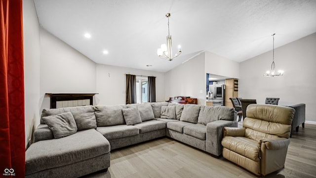 living room with a notable chandelier, lofted ceiling, and light hardwood / wood-style flooring