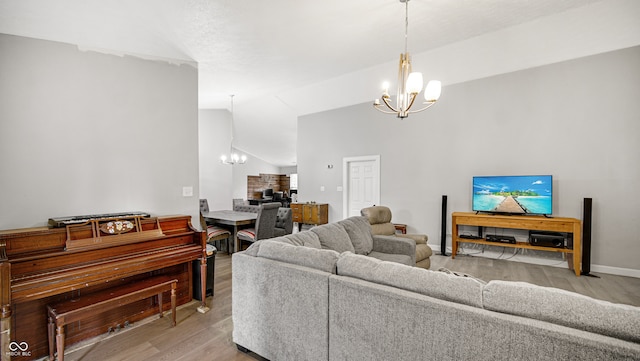 living room featuring an inviting chandelier, lofted ceiling, and light wood-type flooring