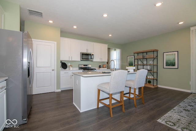 kitchen with stainless steel appliances, dark hardwood / wood-style floors, white cabinets, and a center island with sink