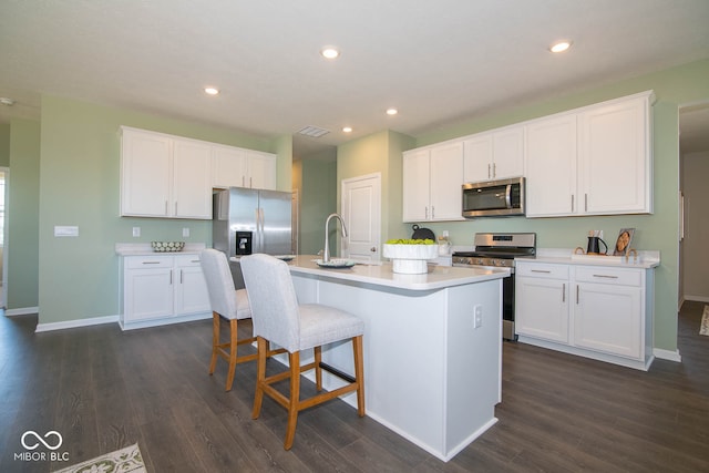 kitchen with white cabinetry, sink, stainless steel appliances, and an island with sink