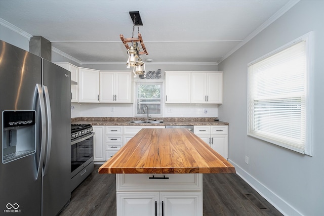 kitchen with a kitchen island, white cabinetry, stainless steel appliances, wooden counters, and decorative light fixtures