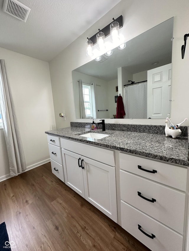 full bath featuring baseboards, visible vents, wood finished floors, and vanity