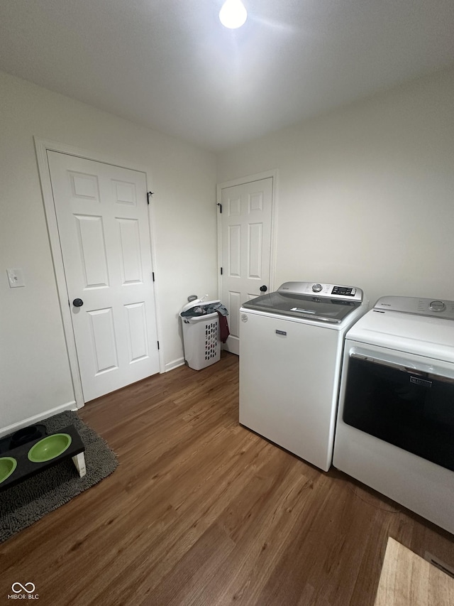 clothes washing area with washer and dryer, laundry area, and wood finished floors