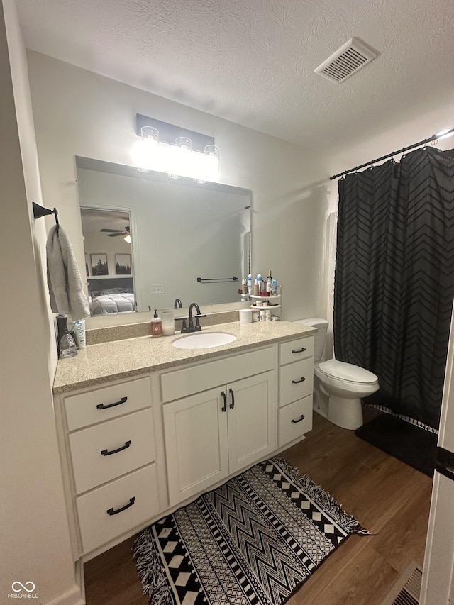 bathroom featuring ceiling fan, vanity, toilet, wood finished floors, and visible vents