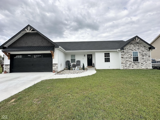 view of front of property featuring an attached garage, a front yard, driveway, and stone siding