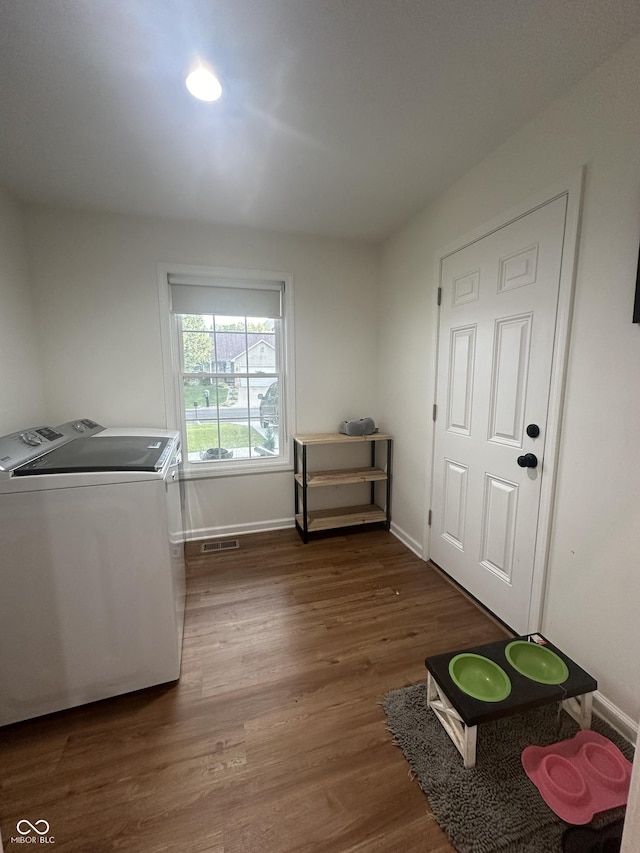 clothes washing area with laundry area, baseboards, wood finished floors, visible vents, and washer and clothes dryer