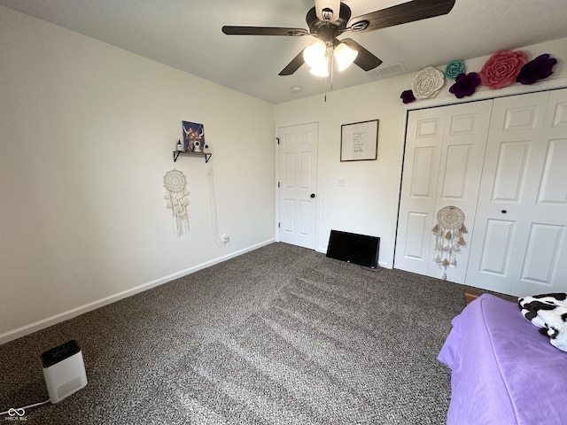 unfurnished bedroom featuring baseboards, ceiling fan, dark carpet, and visible vents