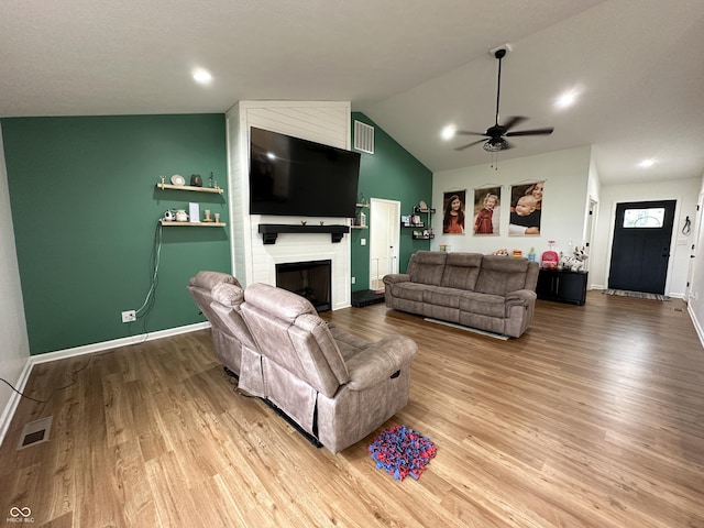 living room with ceiling fan, a fireplace, baseboards, wood finished floors, and visible vents