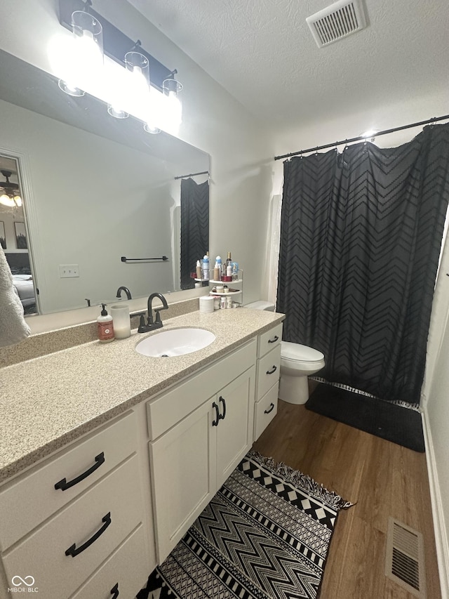 full bathroom featuring toilet, visible vents, wood finished floors, and vanity