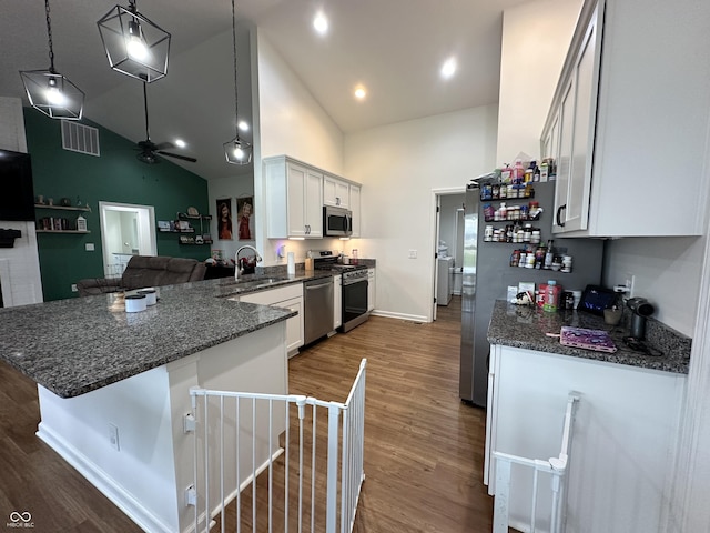 kitchen featuring visible vents, a peninsula, high vaulted ceiling, a sink, and appliances with stainless steel finishes