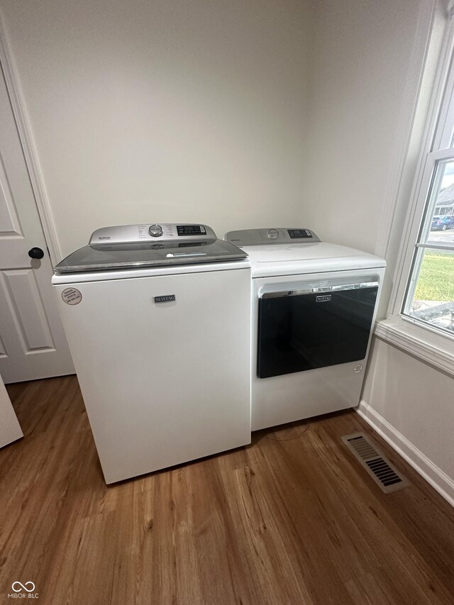 laundry room featuring laundry area, visible vents, washing machine and dryer, and wood finished floors