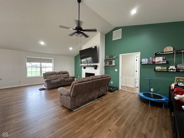 living room with visible vents, lofted ceiling, wood finished floors, a fireplace, and ceiling fan