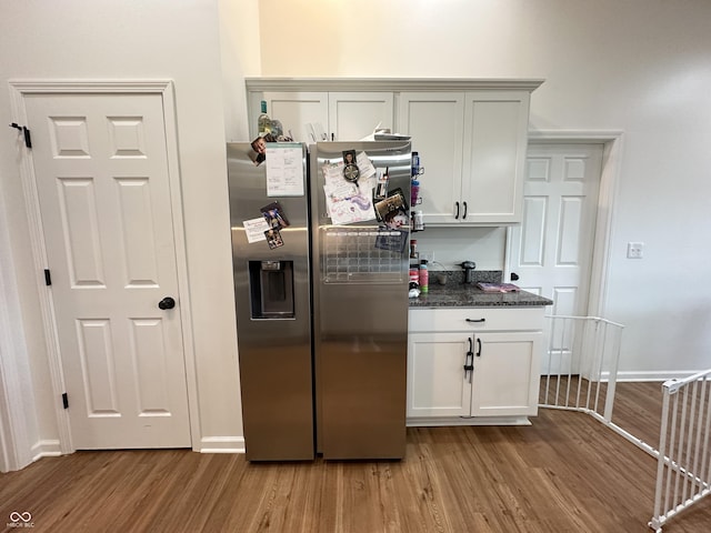 kitchen with stainless steel fridge, baseboards, dark stone counters, and light wood-style flooring