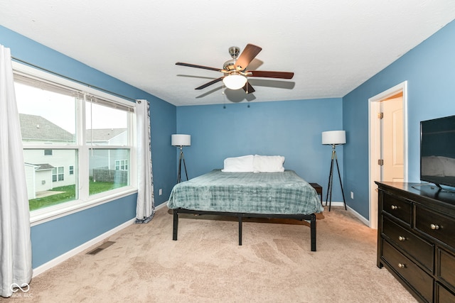 bedroom with ceiling fan, multiple windows, and light colored carpet