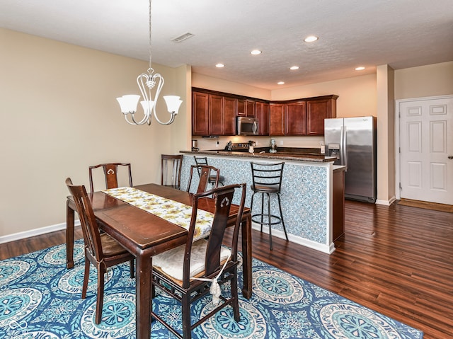 dining area featuring a notable chandelier, dark hardwood / wood-style floors, and a textured ceiling