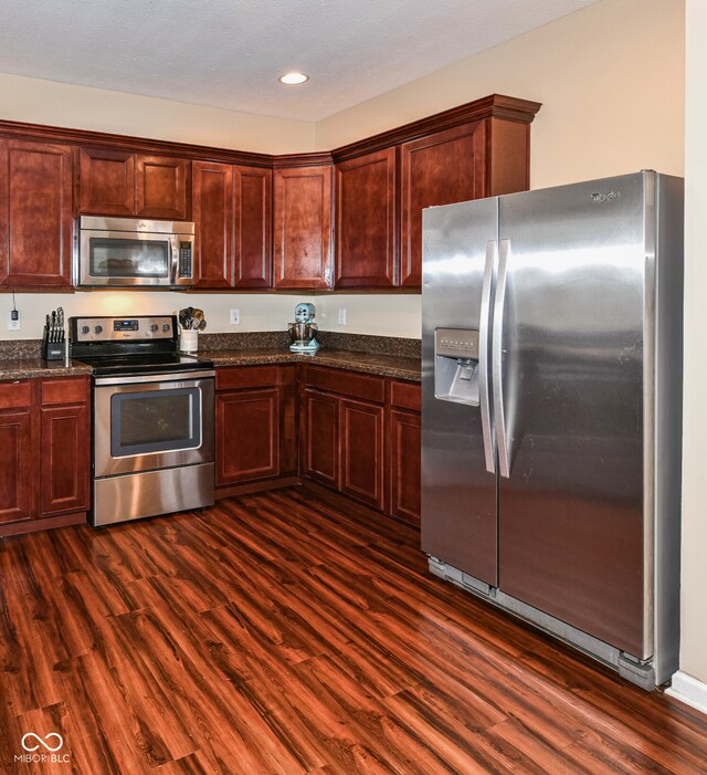 kitchen featuring dark stone countertops, stainless steel appliances, and dark hardwood / wood-style flooring