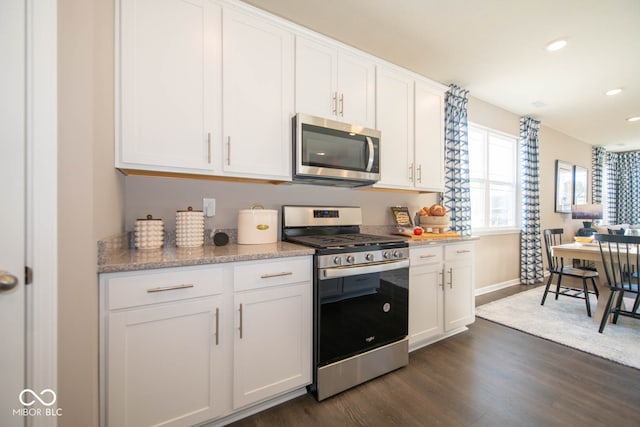 kitchen featuring white cabinets, light stone counters, dark wood-type flooring, and appliances with stainless steel finishes