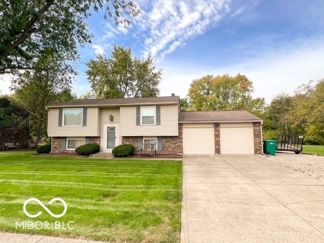 raised ranch featuring a front lawn and a garage