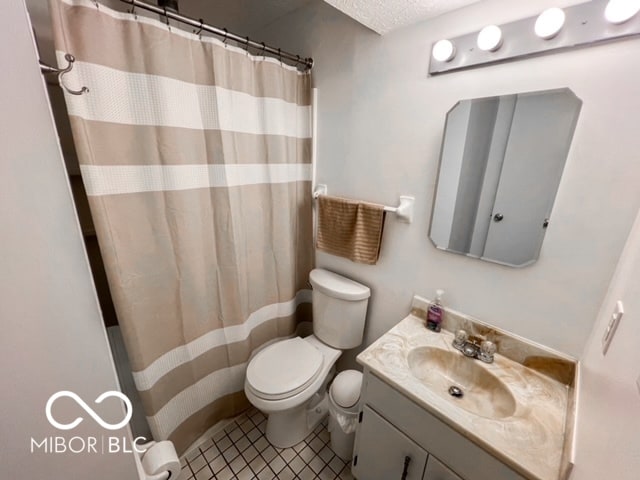 bathroom with a textured ceiling, toilet, a shower with curtain, vanity, and tile patterned flooring