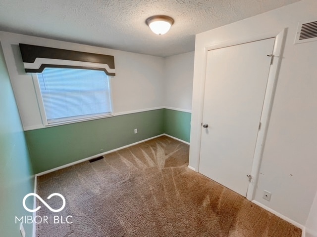 unfurnished bedroom featuring carpet and a textured ceiling