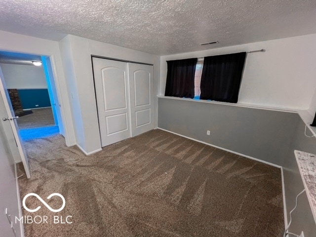 unfurnished bedroom featuring a closet, a textured ceiling, and carpet flooring