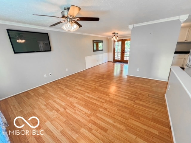 unfurnished living room with french doors, crown molding, light wood-type flooring, a textured ceiling, and ceiling fan with notable chandelier