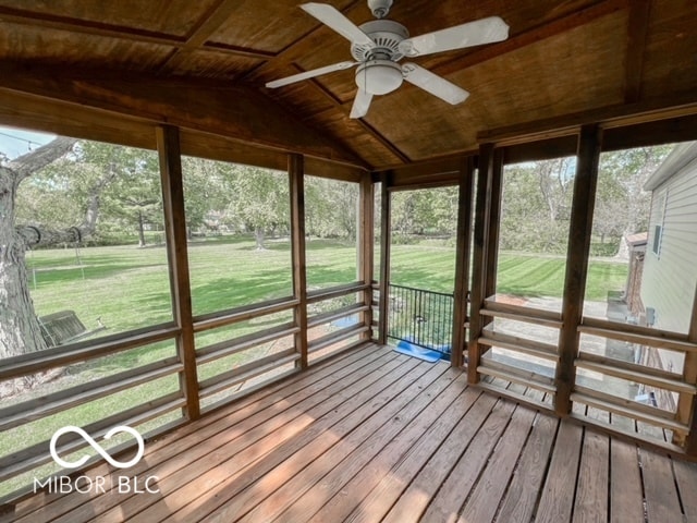 unfurnished sunroom featuring ceiling fan, vaulted ceiling, wood ceiling, and plenty of natural light