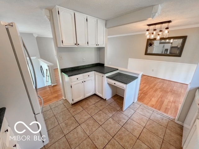 kitchen with a textured ceiling, white cabinetry, light hardwood / wood-style floors, white fridge, and a chandelier