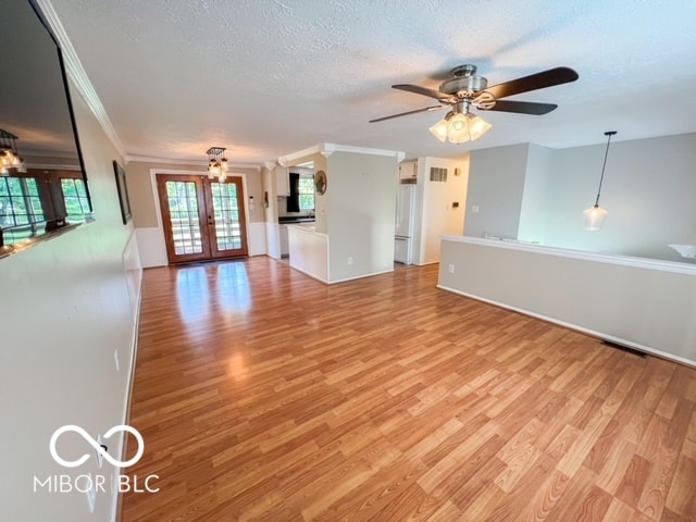 unfurnished living room featuring ornamental molding, french doors, and light hardwood / wood-style flooring