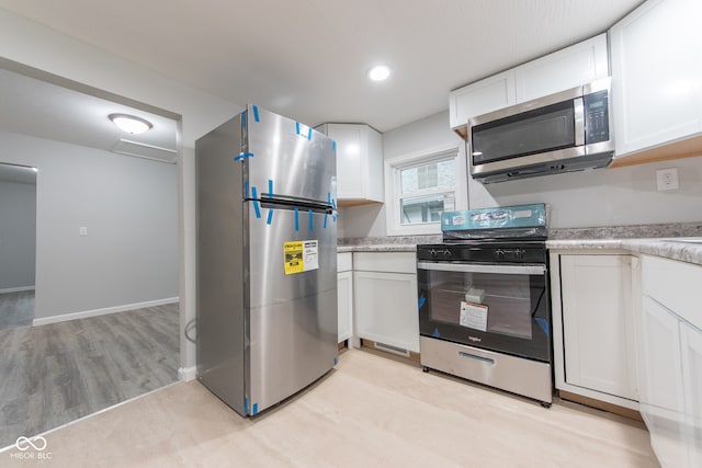 kitchen featuring stainless steel appliances, white cabinetry, and light hardwood / wood-style floors