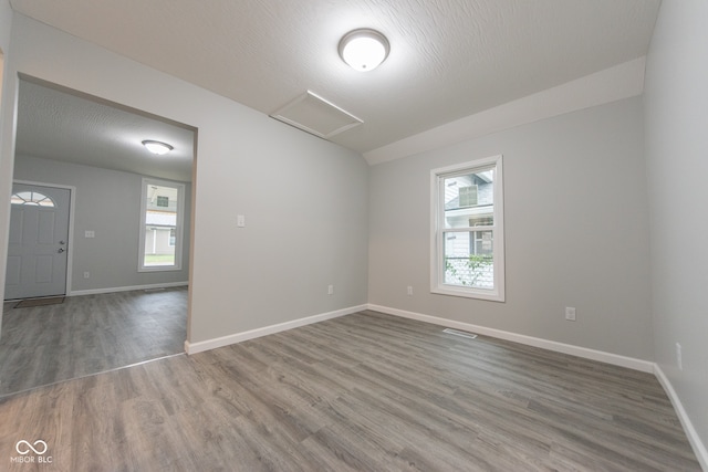 unfurnished room with a textured ceiling, hardwood / wood-style floors, and a healthy amount of sunlight