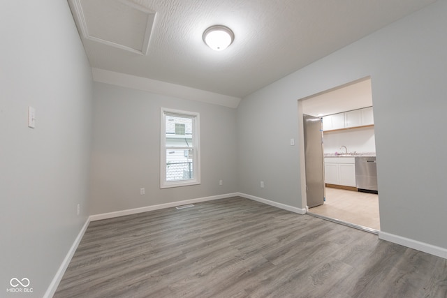 interior space with a textured ceiling, light hardwood / wood-style floors, and sink