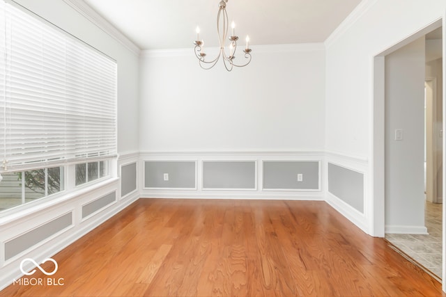 unfurnished dining area featuring an inviting chandelier, crown molding, and hardwood / wood-style floors