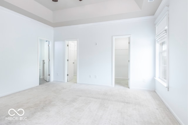 unfurnished bedroom featuring light colored carpet, a closet, ensuite bathroom, and a walk in closet