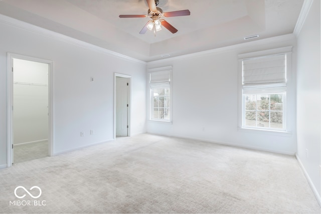 unfurnished room featuring light carpet, a tray ceiling, ceiling fan, and ornamental molding