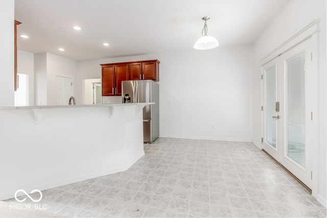 kitchen featuring hanging light fixtures, a breakfast bar, kitchen peninsula, stainless steel refrigerator with ice dispenser, and sink