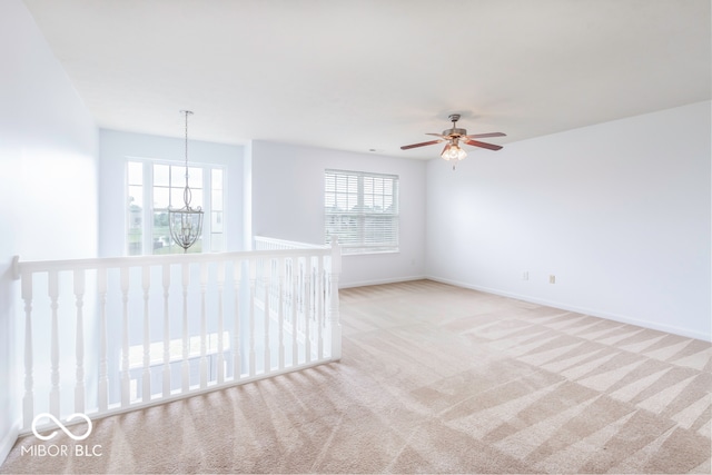 unfurnished room with ceiling fan with notable chandelier, light carpet, and a healthy amount of sunlight