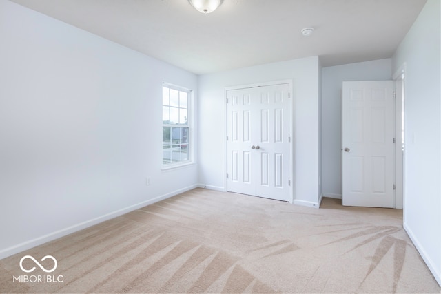 unfurnished bedroom with light carpet and a closet