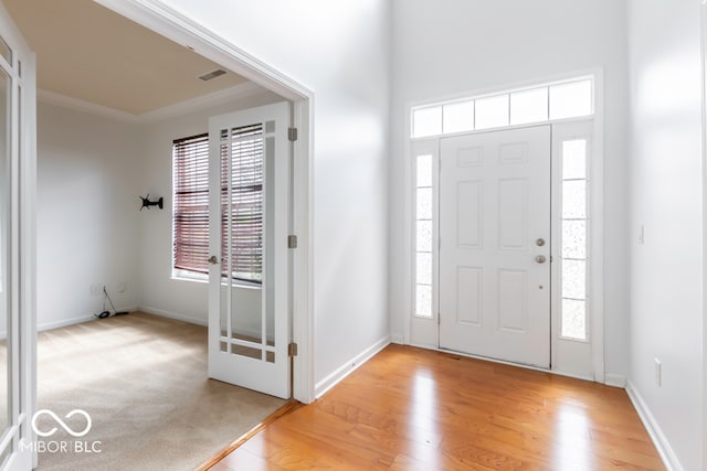 entryway featuring crown molding, light hardwood / wood-style floors, and plenty of natural light