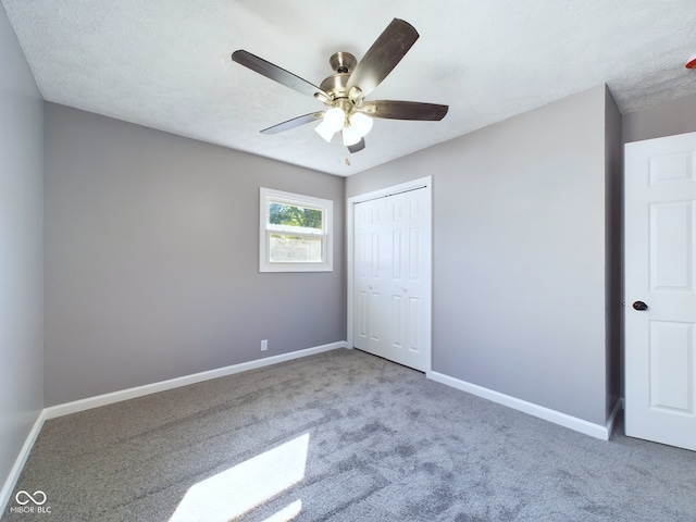 unfurnished bedroom with a closet, carpet, ceiling fan, and a textured ceiling