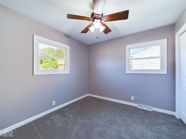 carpeted spare room featuring ceiling fan and plenty of natural light