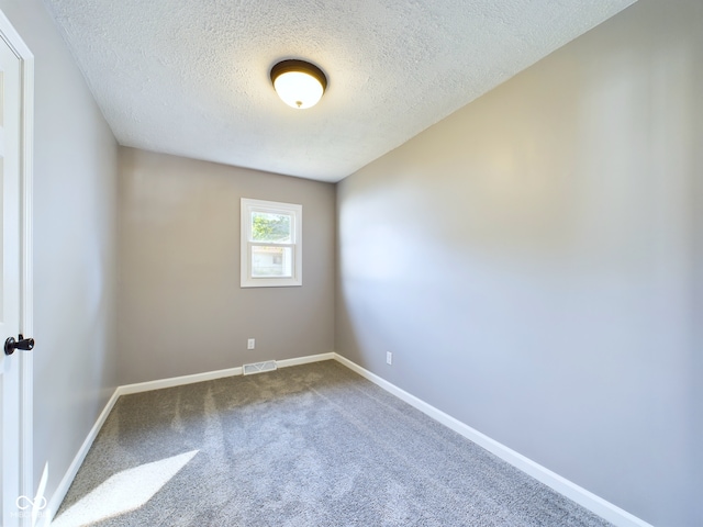 carpeted empty room with a textured ceiling